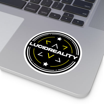 Round Lucid Reality logo sticker applied to a laptop, showing the black shield design with white "LUCID REALITY" text.