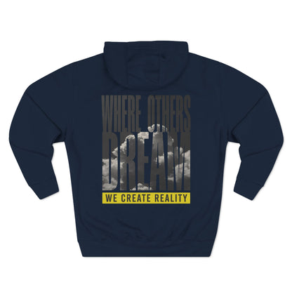 Back of the navy Where Others Dream Fleece Pullover Hoodie with the city skyline graphic and yellow We Create Reality banner.