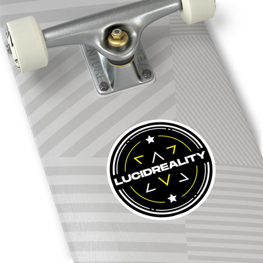 Round Lucid Reality logo sticker applied to the bottom of a skateboard deck, featuring the black circular shield design with white "LUCID REALITY" text.
