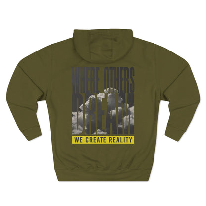 Back of the army green Where Others Dream Fleece Pullover Hoodie with the city skyline graphic and yellow We Create Reality banner.