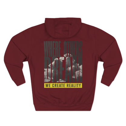 Back of the burgundy Where Others Dream Fleece Pullover Hoodie with the city skyline graphic and yellow We Create Reality banner.