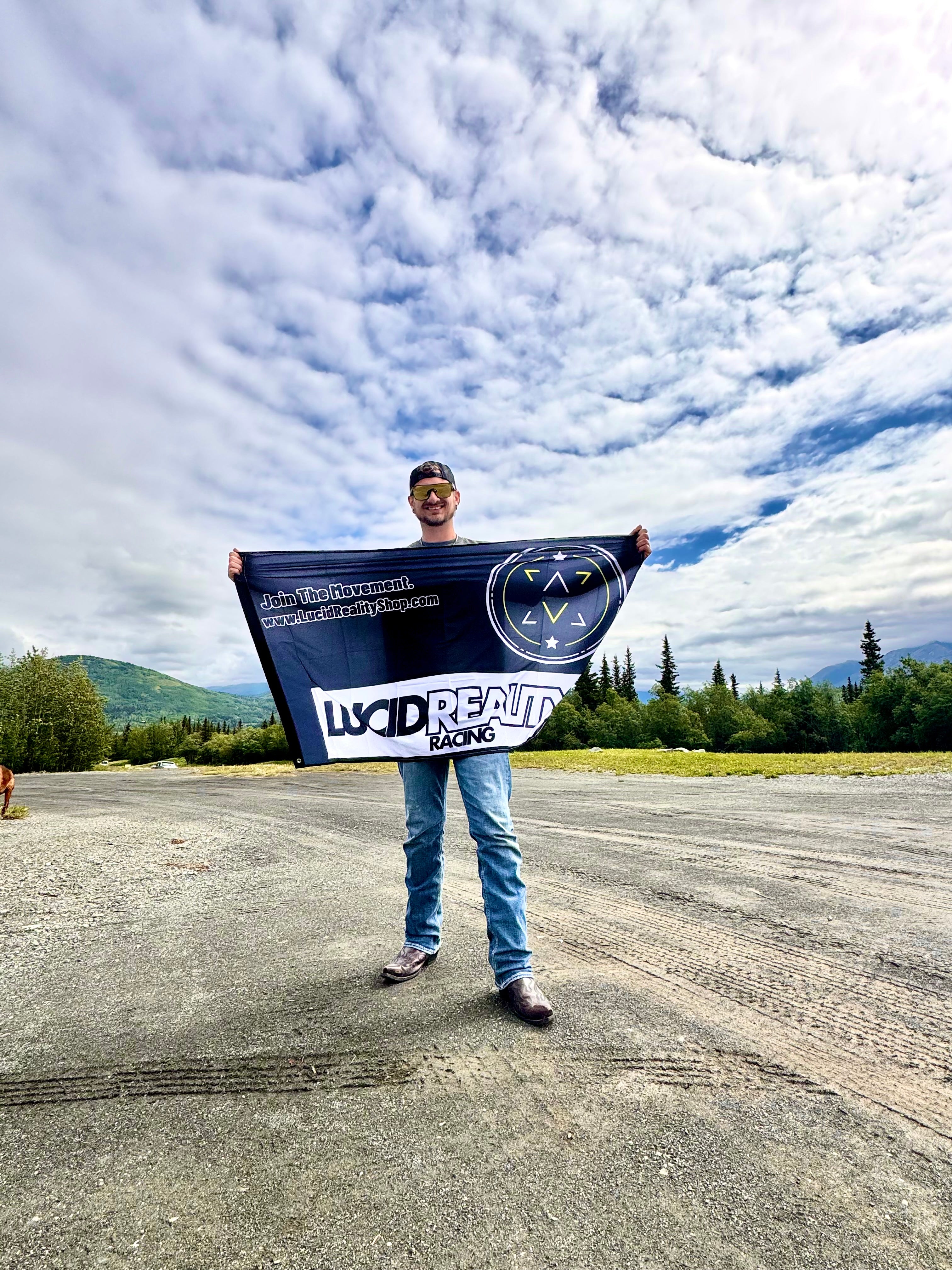 Person holding a large banner with text and logos against a cloudy sky