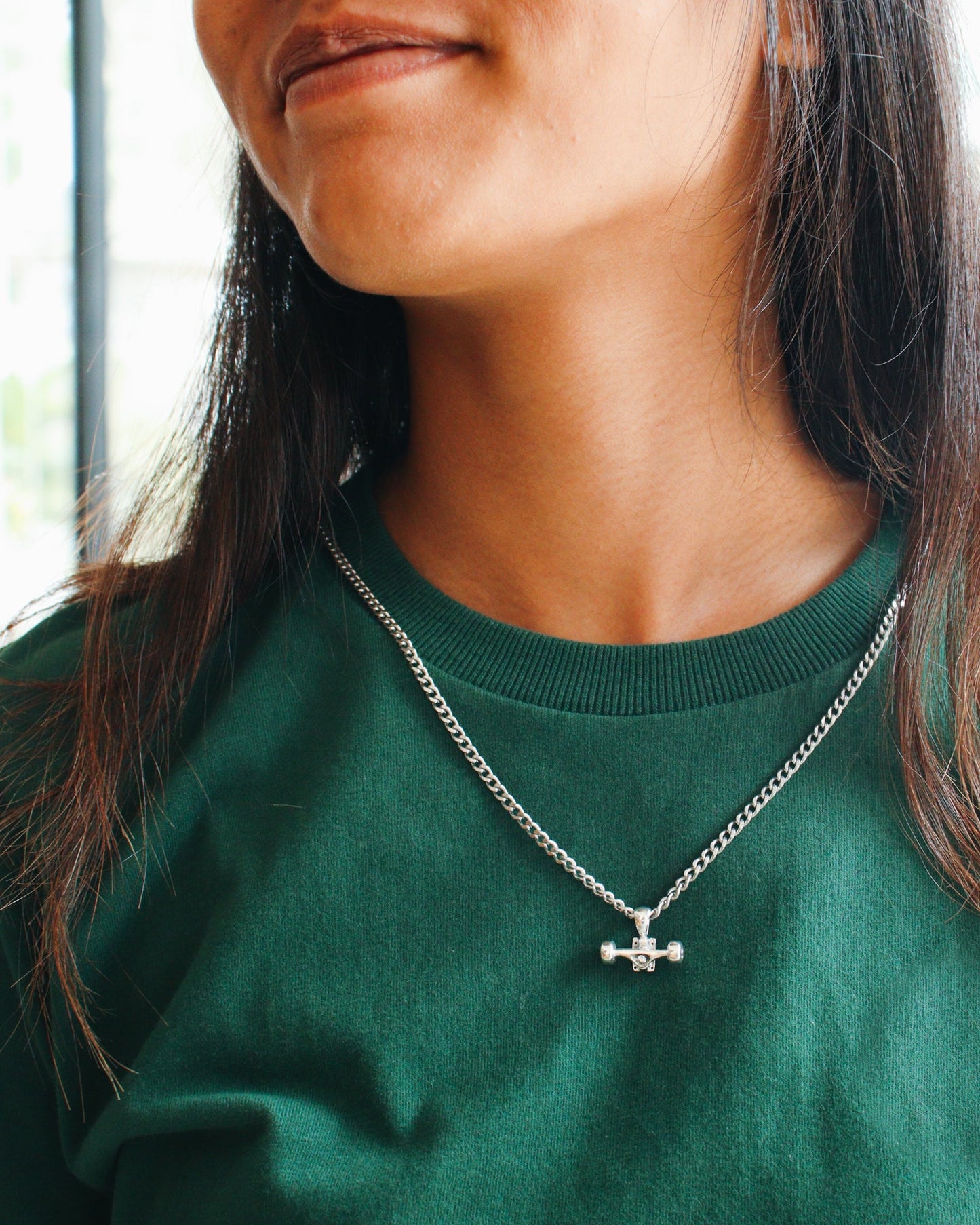 Sterling silver skateboard truck with wheels pendant on a Cuban chain, curated by Lucid Reality