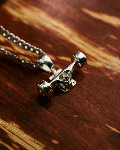Sterling silver skateboard truck with wheels pendant on a Cuban chain, curated by Lucid Reality